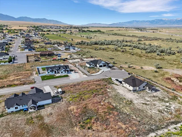 Expansive aerial perspective showcasing a developed residential area with scattered homes and mountain ranges in the distance