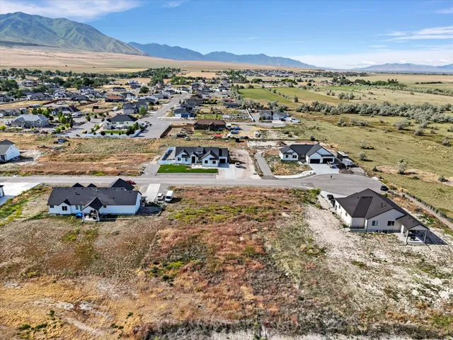 Expansive rural landscape featuring a residential community with contemporary homes, mountain backdrop, and clear sky