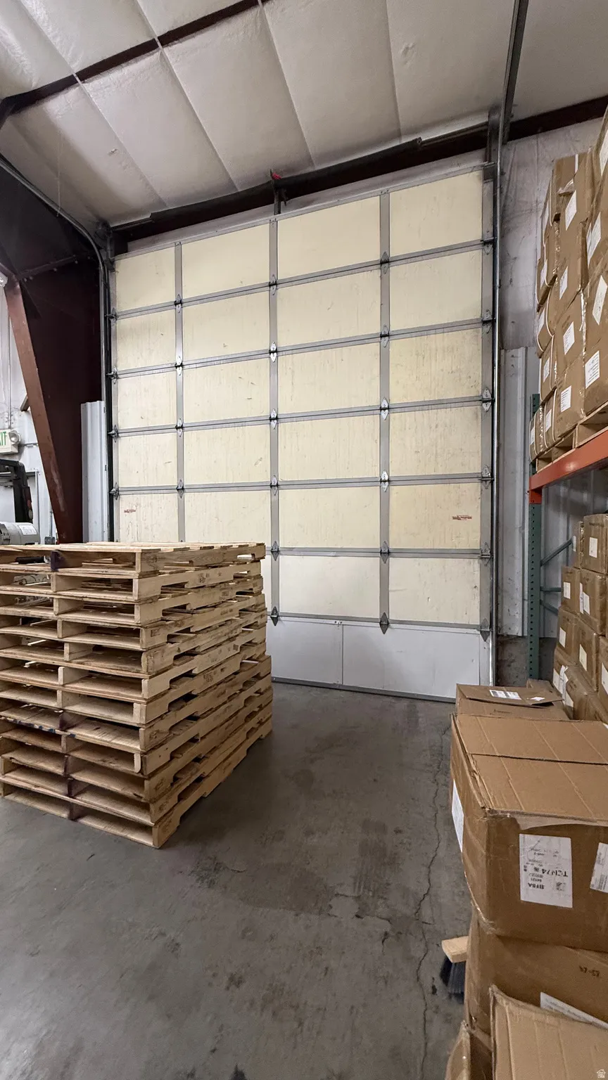 Industrial overhead door with panel construction, exposed metal framing, and a concrete floor