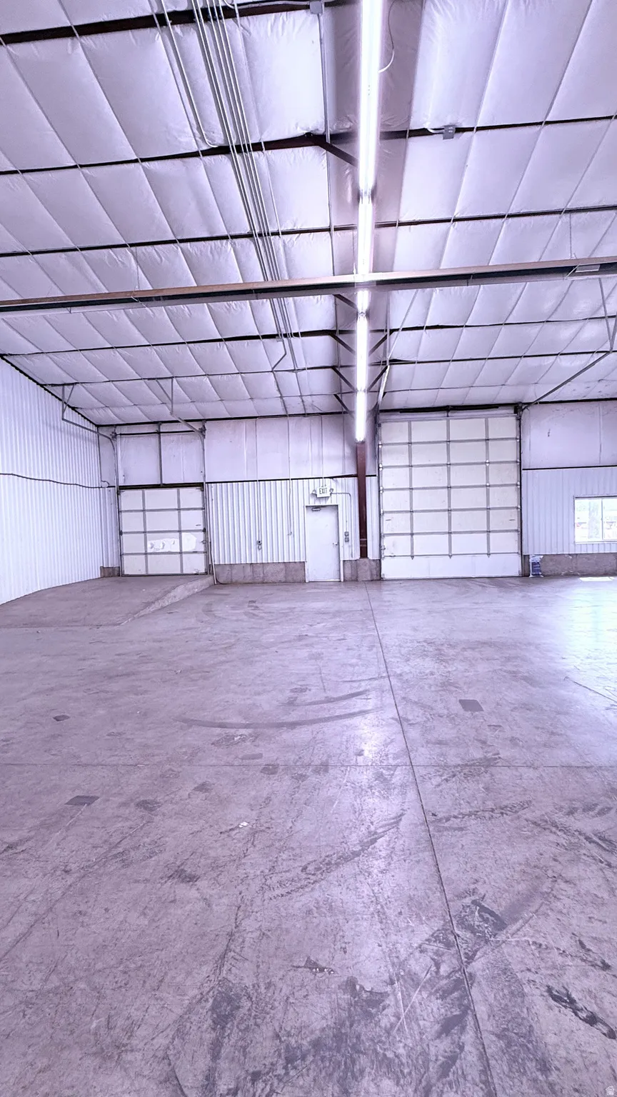 Polished concrete flooring, multiple overhead doors, exposed overhead utilities, and insulated ceiling panels