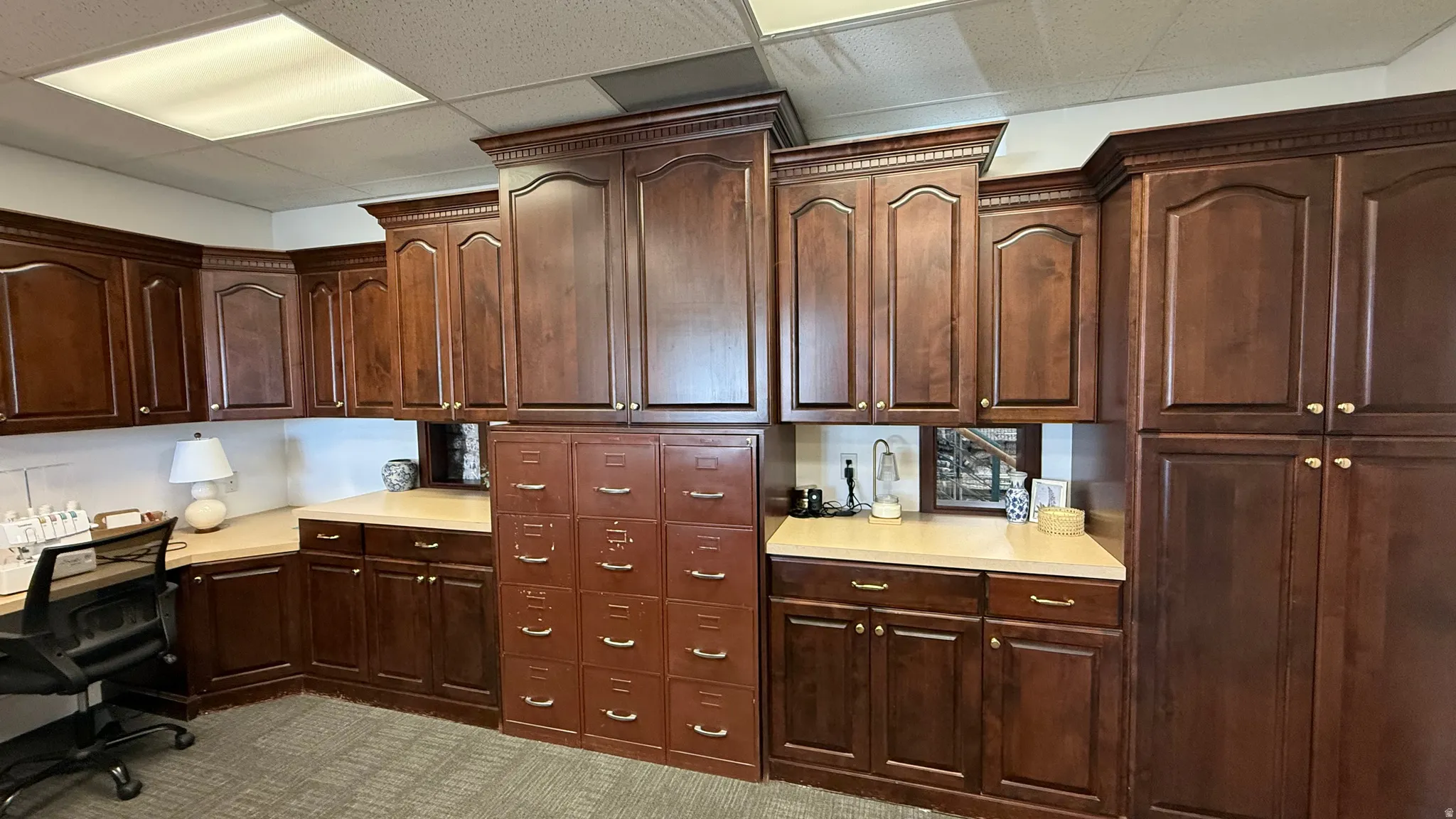 Extensive cabinetry installation featuring dark wood-finish doors, detailed crown molding, and light-toned countertops