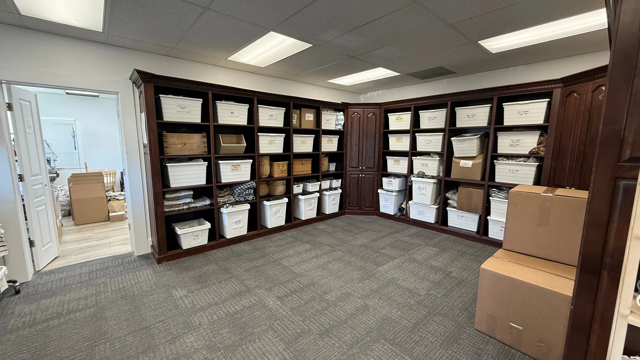 Built-in dark wood shelving and cabinetry with ample storage, recessed ceiling lighting, and gray patterned carpet flooring