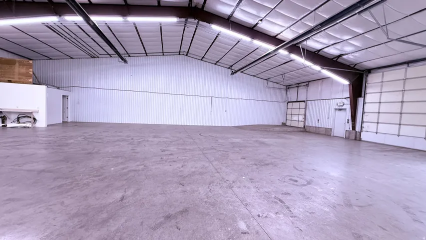 Spacious concrete flooring, corrugated metal walls, exposed structural beams, high ceilings, and multiple overhead doors