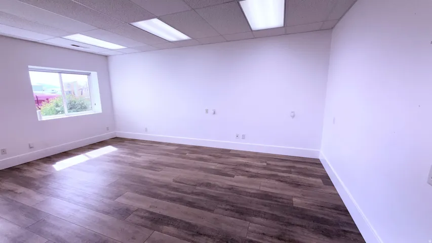 Wood-finish flooring, white walls, and a drop ceiling with recessed lighting