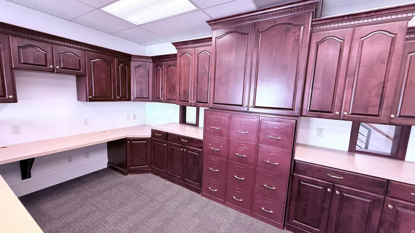 Extensive built-in wood cabinetry with decorative molding and gold-tone hardware, file storage, and integrated countertops