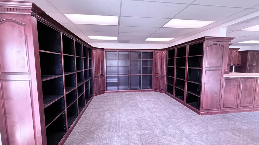 Extensive built-in shelving with a rich wood finish, integrated cabinetry with a wood finish, textured carpet flooring, and recessed ceiling lighting