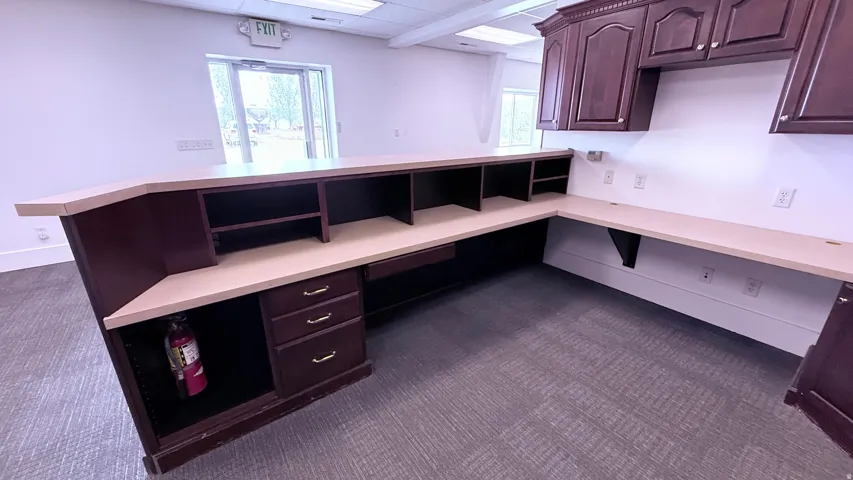 Built-in reception desk with a light-toned countertop, integrated cabinetry, and overhead storage