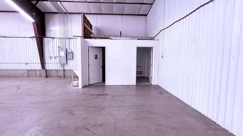 Polished concrete flooring, corrugated metal walls, structural steel beams, white interior doors, and overhead lighting fixtures