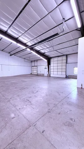 Expansive concrete flooring throughout, featuring a high ceiling with exposed structural beams and insulated panels
