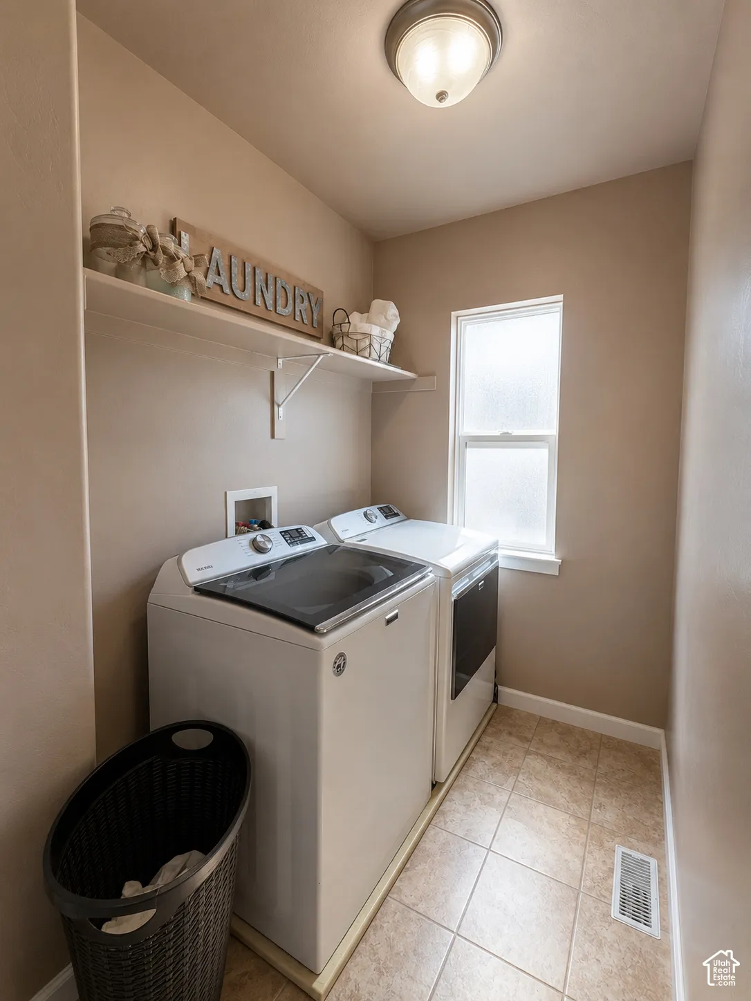 Dedicated laundry area featuring a window, built-in shelving, and tile flooring