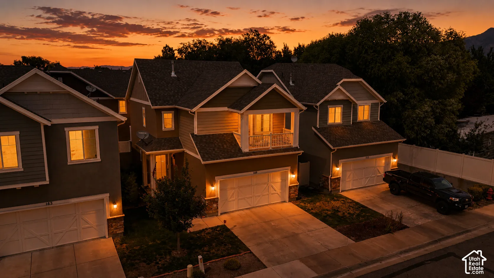 Two-story residence featuring a balcony, attached two-car garage, and stone veneer accents