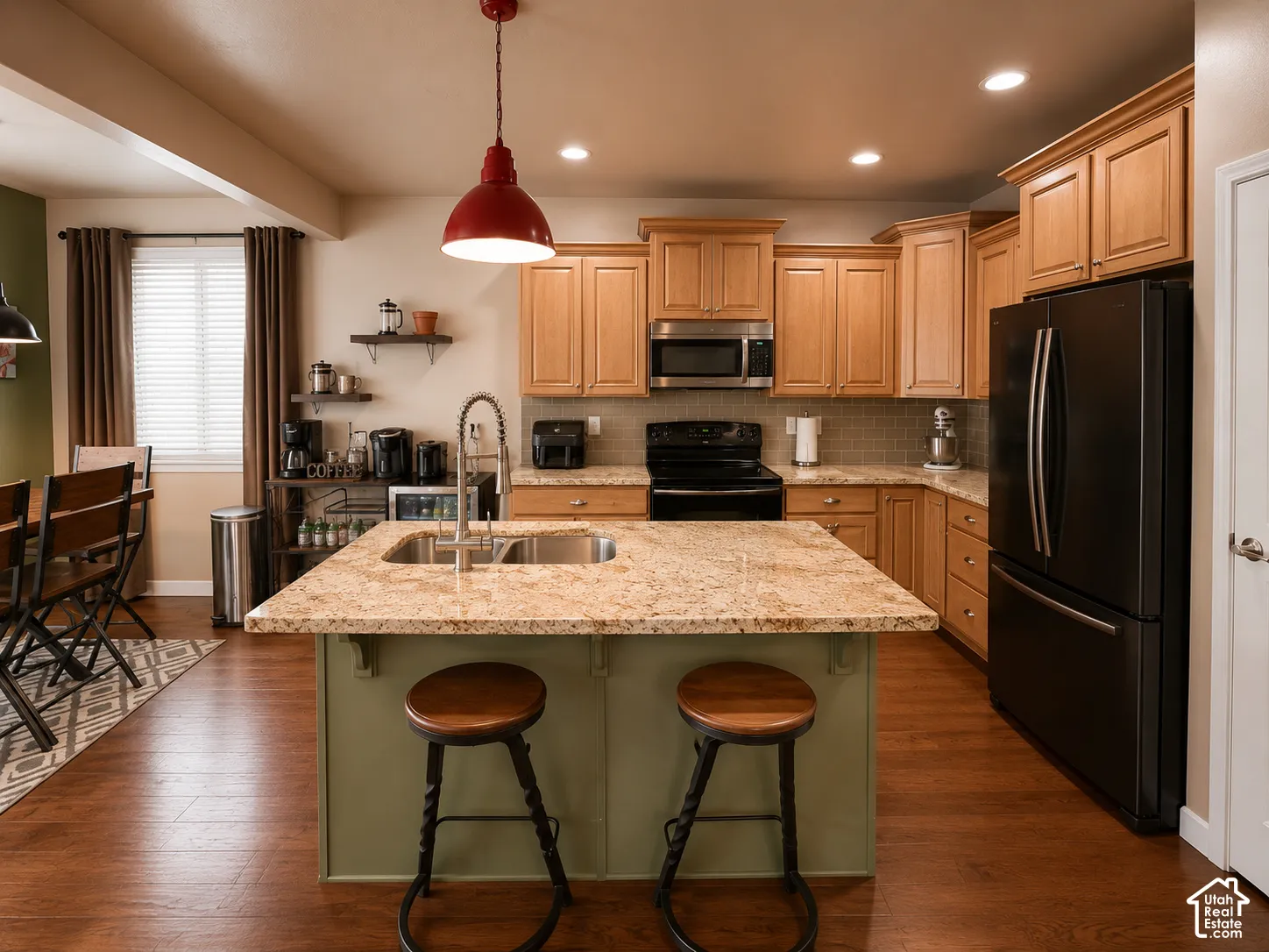Kitchen featuring a central island with a dual-basin sink, light-toned cabinetry, and dark-finish appliances
