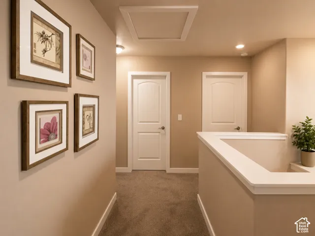 Carpeted hallway featuring a recessed ceiling light, white trim, and a white interior door