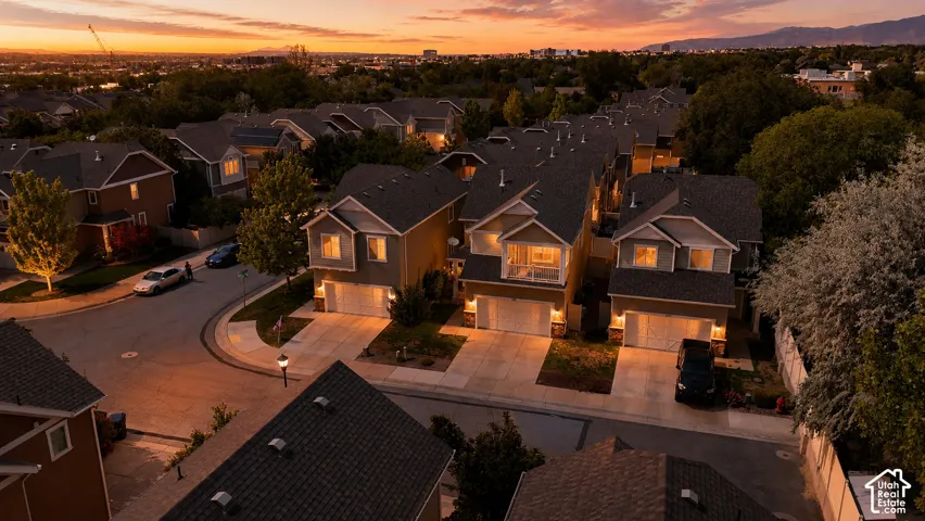 Residential street featuring multi-story homes with attached garages, individual driveways, and landscaped front yards