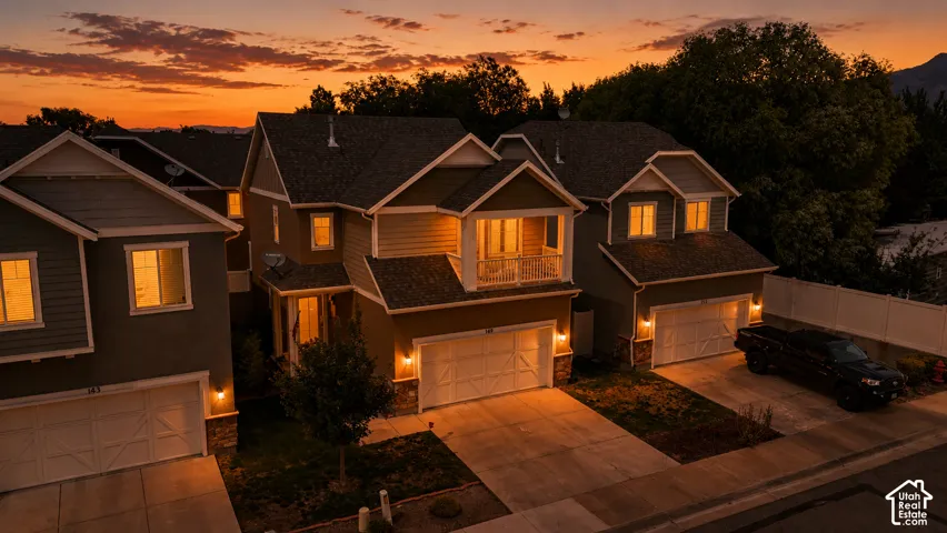 Two-story residence featuring a balcony, attached two-car garage, and stone veneer accents