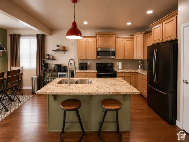 Kitchen featuring a central island with a dual-basin sink, light-toned cabinetry, and dark-finish appliances