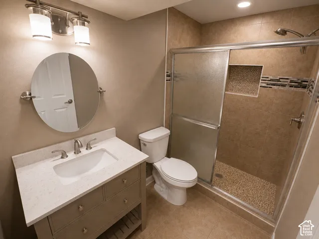 Bathroom featuring a single vanity with stone-finish countertop, brushed nickel faucet, and a circular mirror