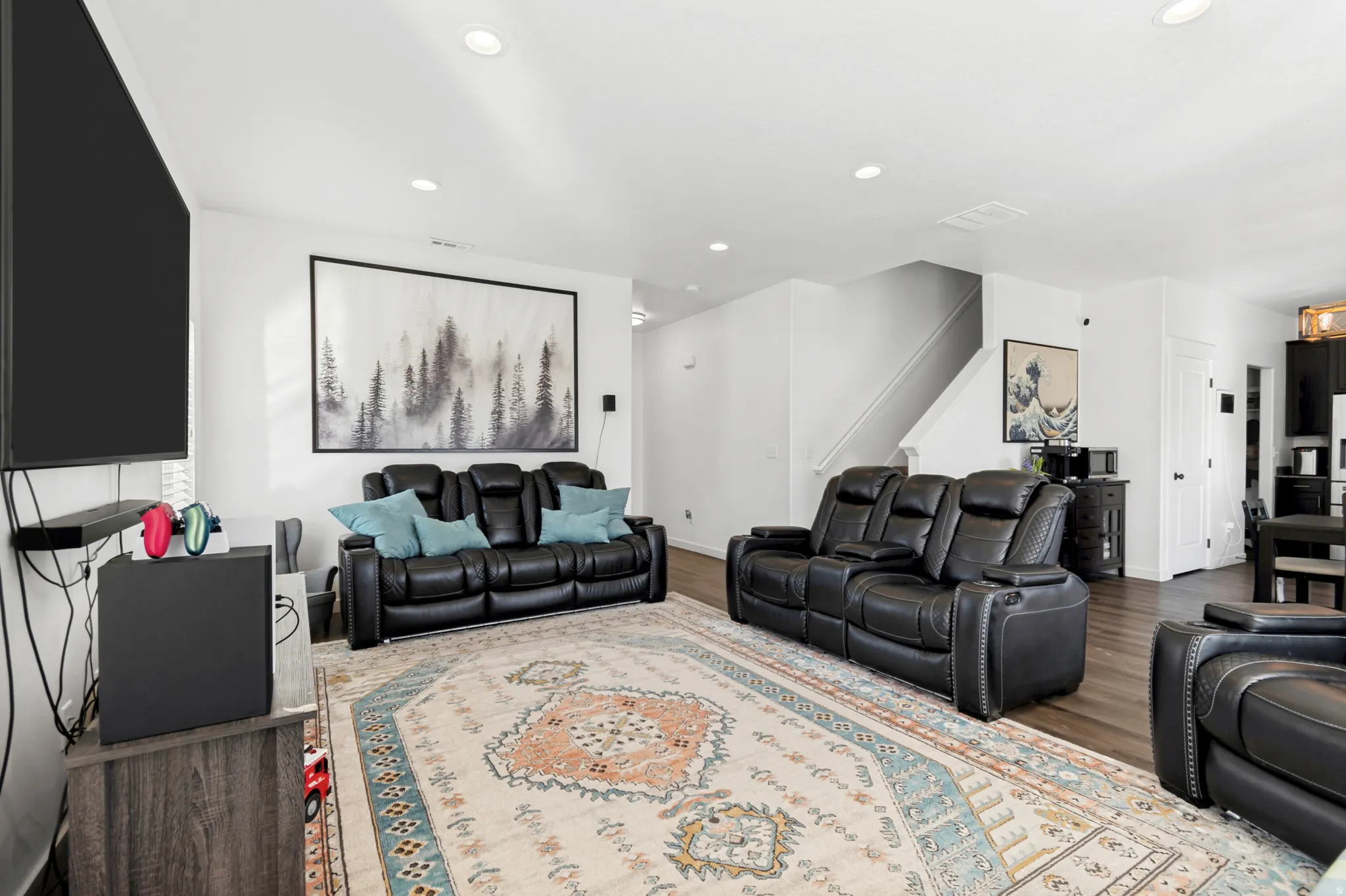 Open-concept living space featuring wood-finish flooring, white walls, and recessed lighting