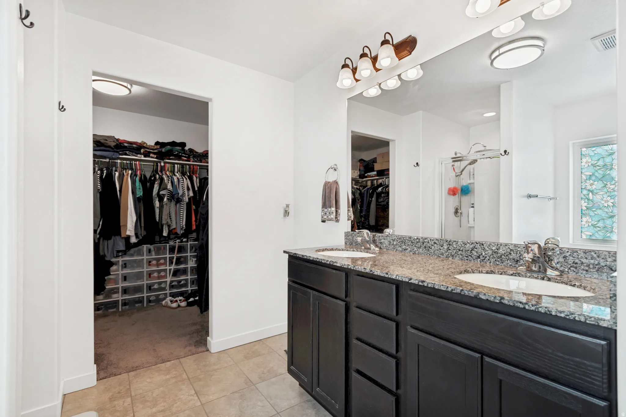 Double vanity with integrated sinks, speckled countertop, and dark wood-finish cabinetry