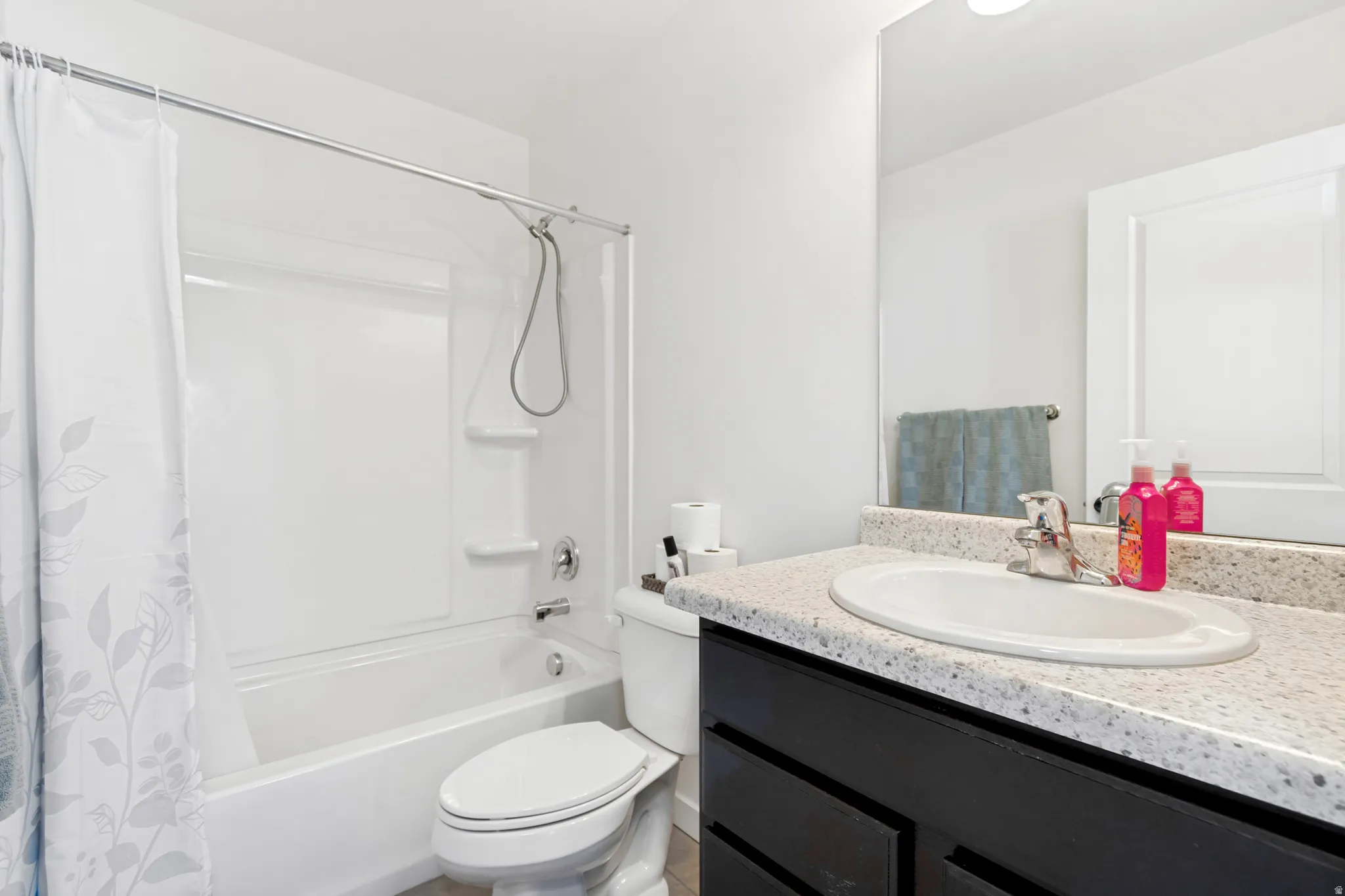 Bathroom featuring a white tub-shower combination with a chrome showerhead, a toilet, and a vanity with a white oval sink