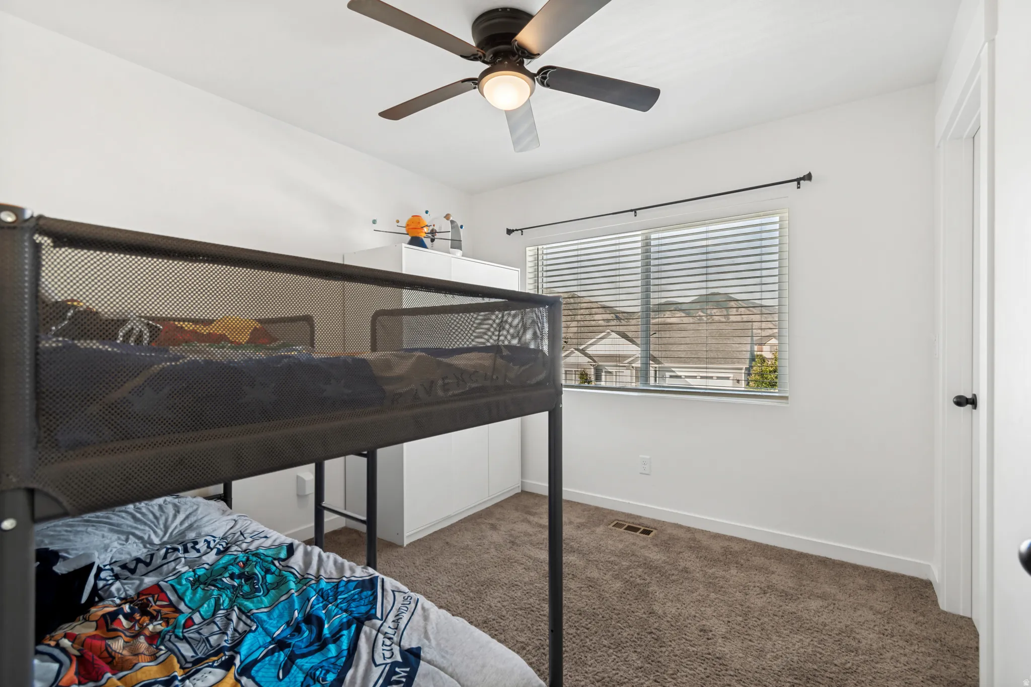 Bright room featuring a ceiling fan with integrated lighting, a window with horizontal blinds, and neutral carpeting