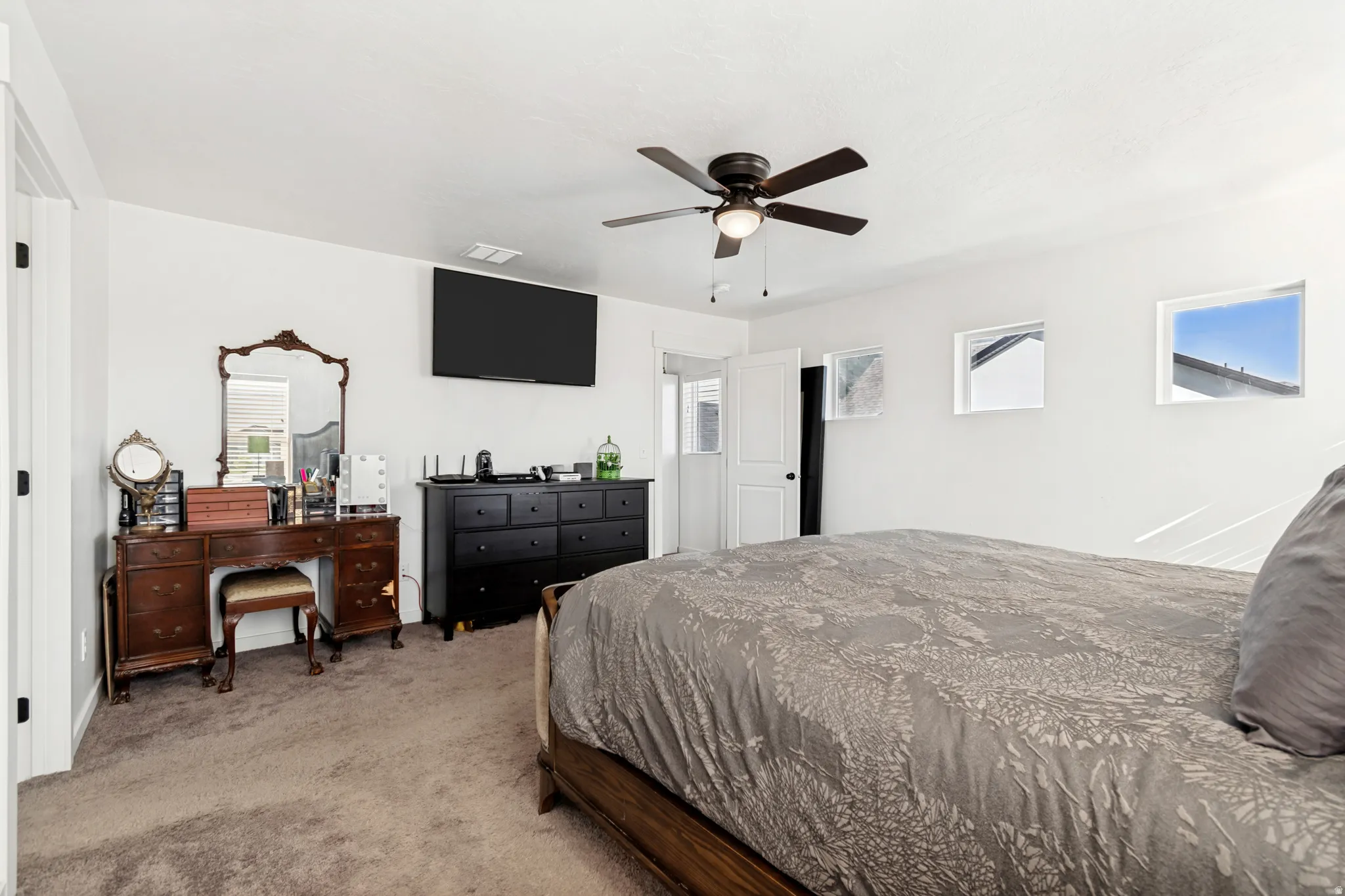 Carpeted room featuring white walls and a ceiling fan with integrated lighting