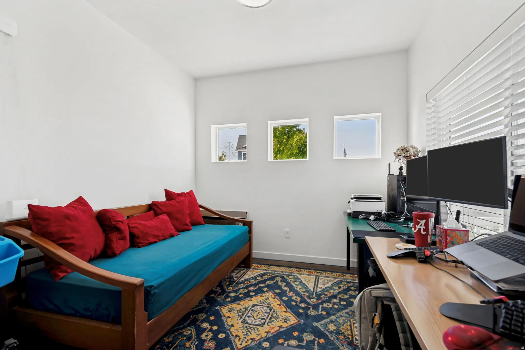 Bright interior space featuring three square windows, a wood-finish flooring, and white walls