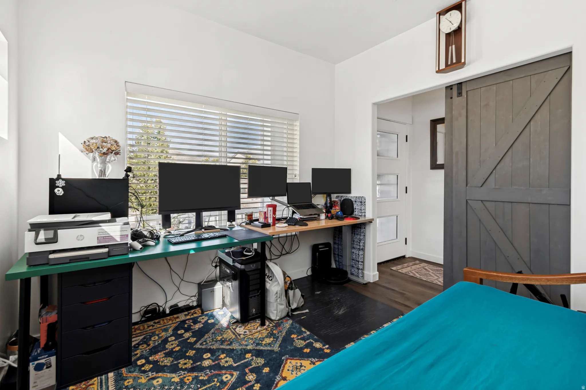 Bright room featuring a large window with blinds, dark wood-finish flooring, and a barn-style sliding door