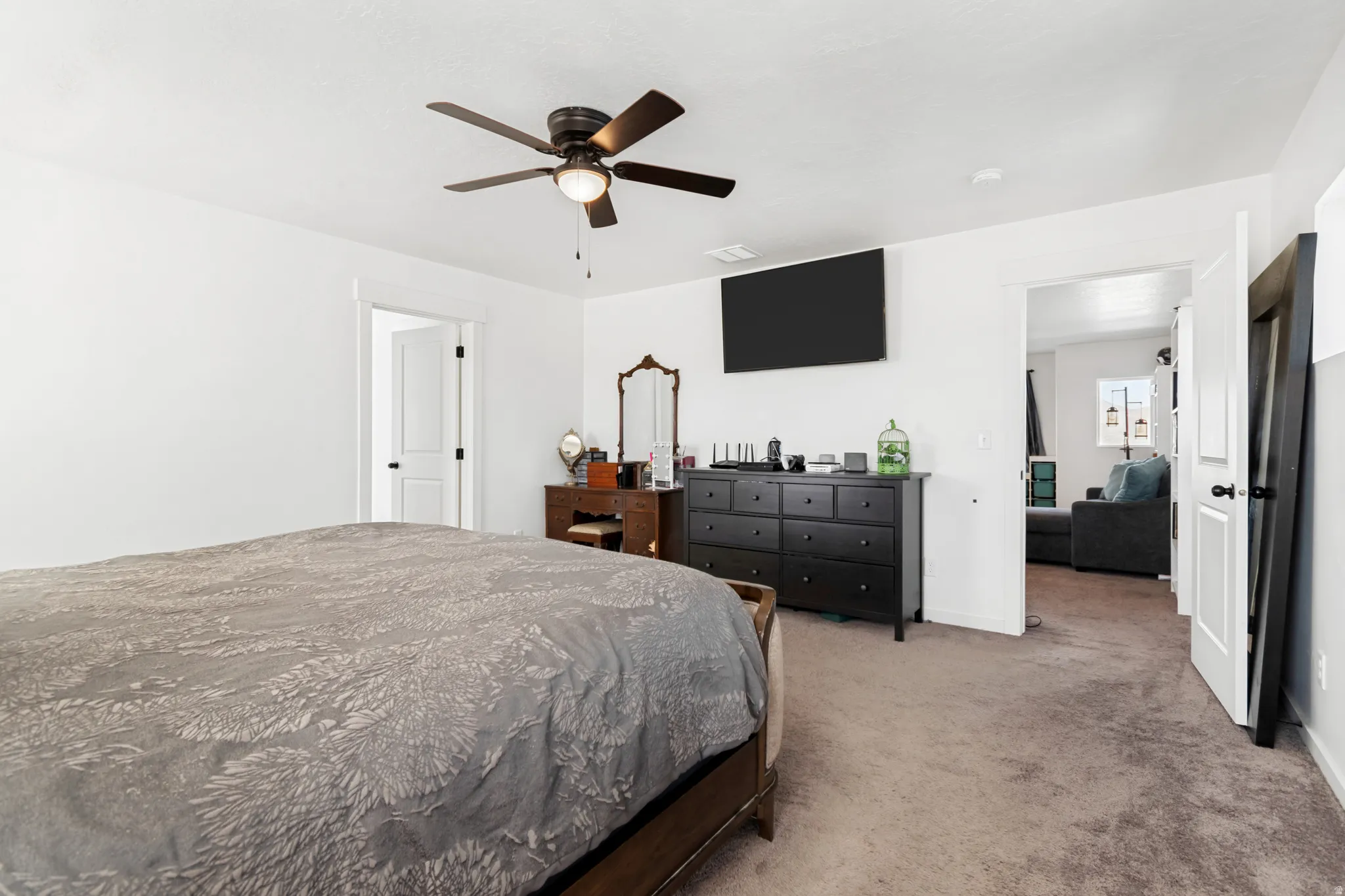 Spacious room featuring carpet flooring, white walls, and a ceiling fan with integrated lighting
