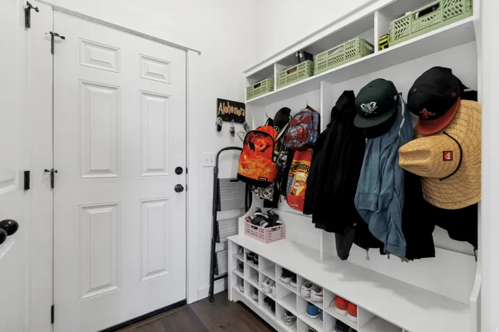 Dedicated mudroom area featuring built-in shelving, coat hooks, and shoe cubbies