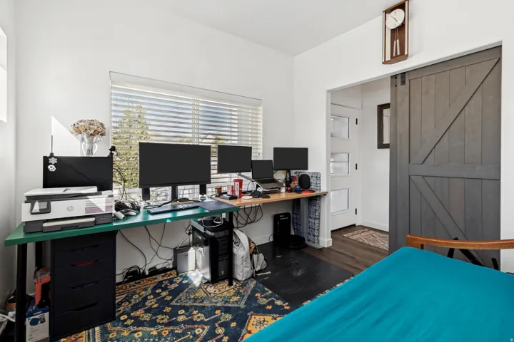 Bright room featuring a large window with blinds, dark wood-finish flooring, and a barn-style sliding door