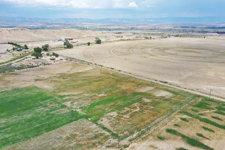 Expansive rural landscape featuring a mix of cultivated green fields and arid open land