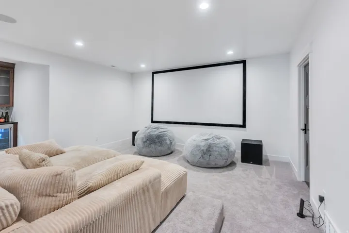 Dedicated media room featuring a large projection screen, recessed lighting, and soft gray carpeting