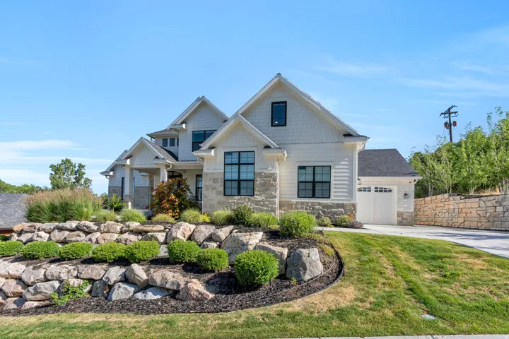 Multi-level residence featuring a stone and shingle facade, prominent gables, and dark-framed windows