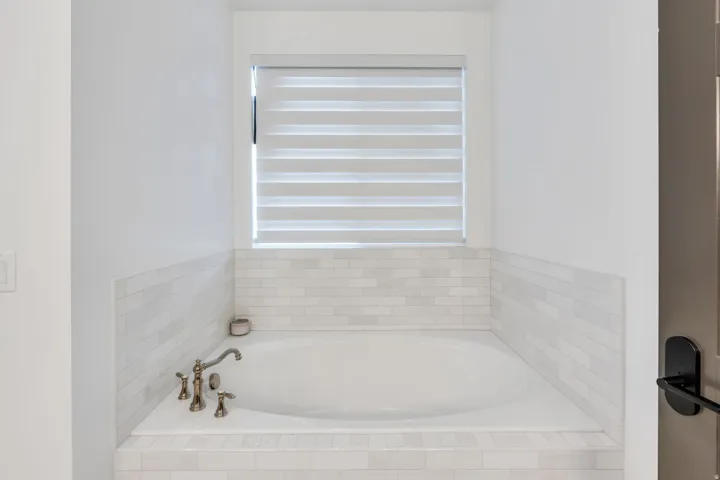 Built-in soaking tub featuring a decorative tile surround and wall wainscoting