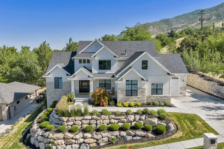 Contemporary residence featuring a pitched roofline, white siding, and stone accents