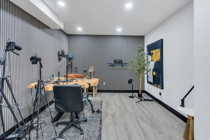 Dedicated room featuring vertical slat wall paneling, recessed lighting, and wood-finish flooring
