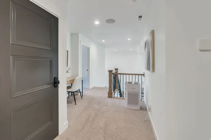 White walls with recessed lighting illuminate a carpeted hallway