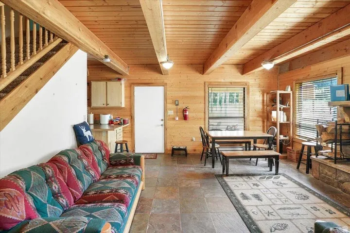 Spacious open-concept interior featuring light wood paneling throughout, exposed ceiling beams, and slate-finish flooring