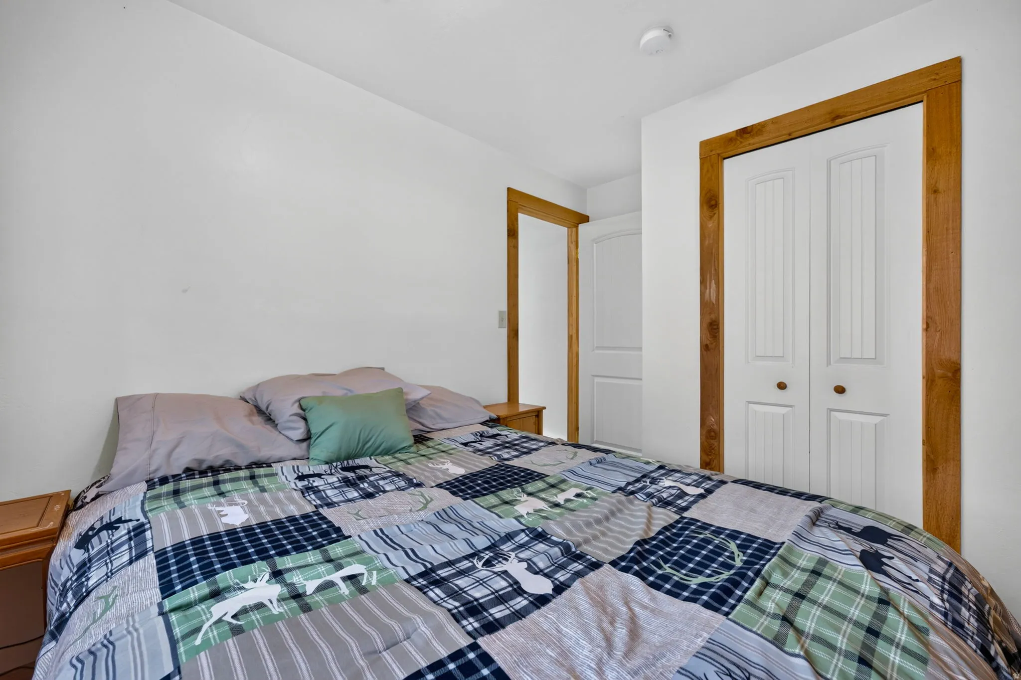 White walls with natural wood trim framing a bi-fold closet door and an additional door