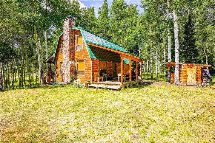 Log cabin style residence with a gambrel roof and a covered porch