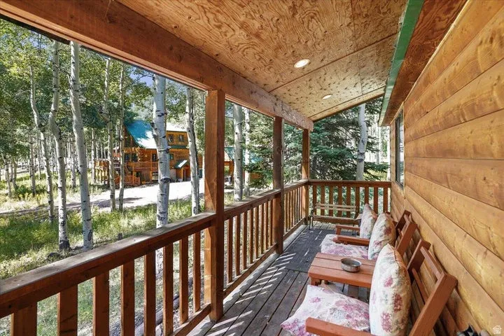 Covered wood deck with natural wood siding, wood-finish flooring, and recessed ceiling lighting