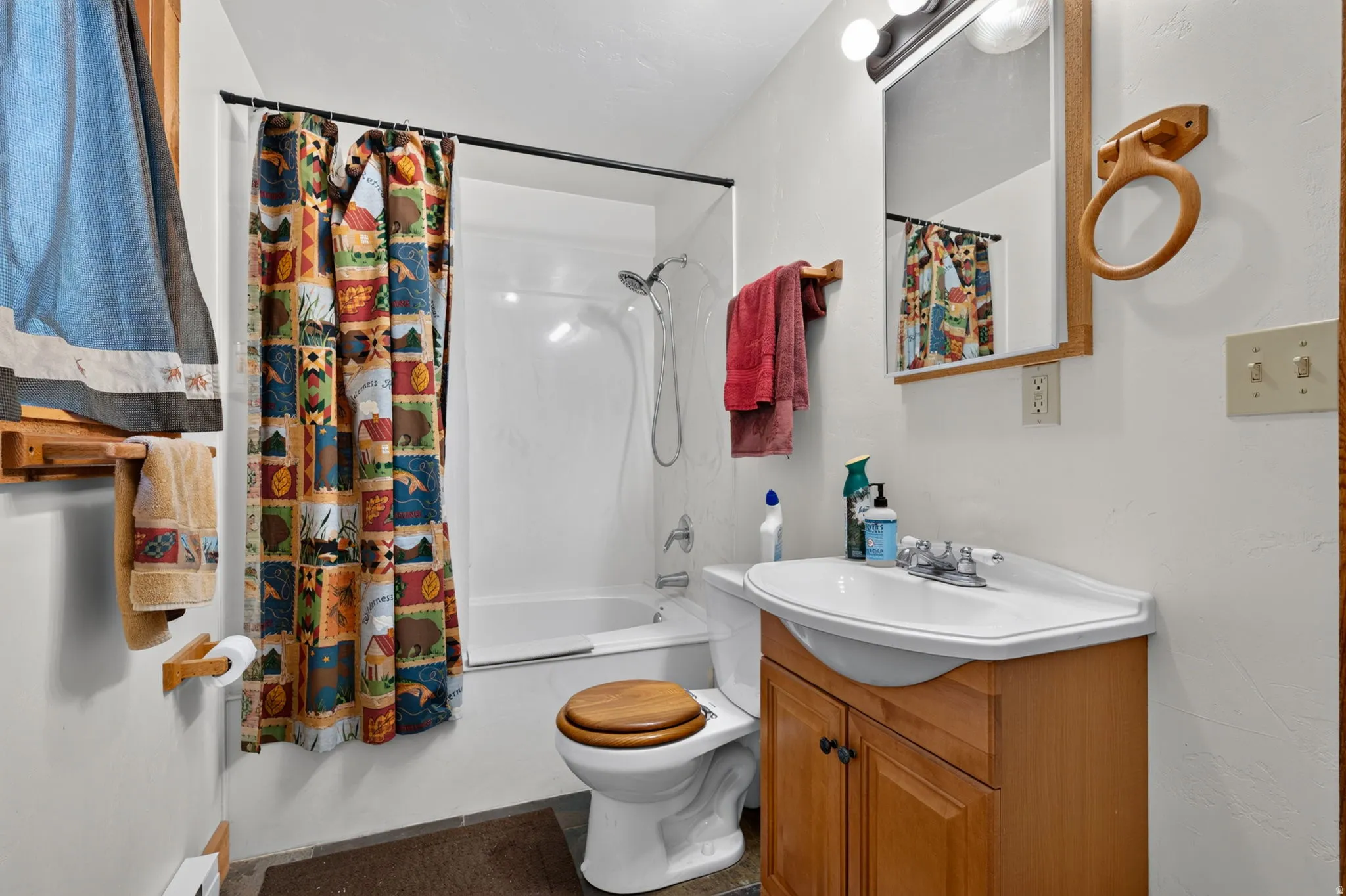 Full bathroom featuring a white tub/shower combination, light wood-finish vanity with an integrated sink, and coordinating wood-finish mirror framing