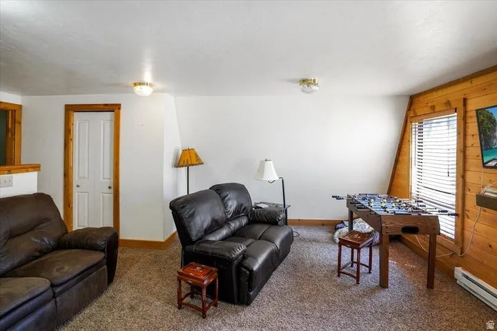 Spacious room featuring light-colored walls, wood-paneled accents, and a sloped ceiling
