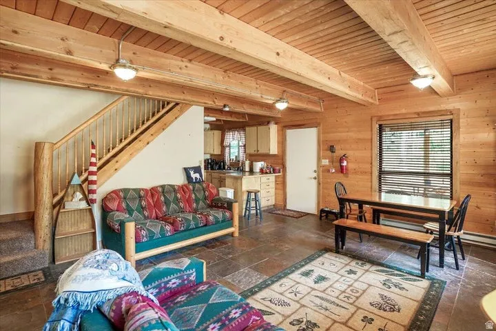 Open-concept living space with exposed wood beams and wood-paneled walls