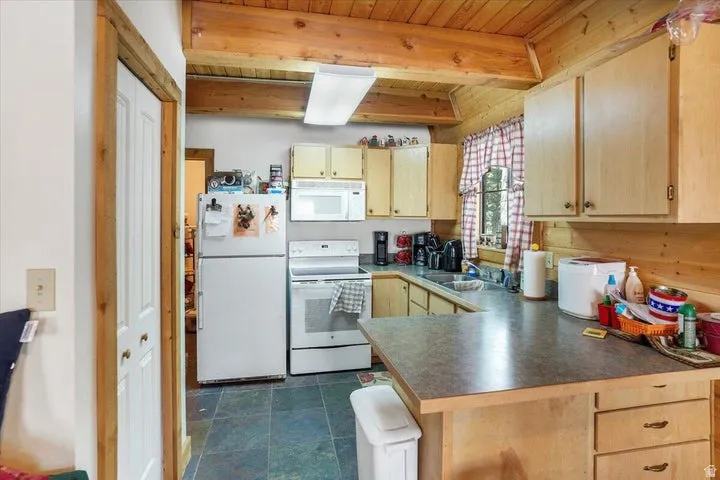 Kitchen featuring wood-finish cabinetry, a laminate countertop, and full-size white appliances