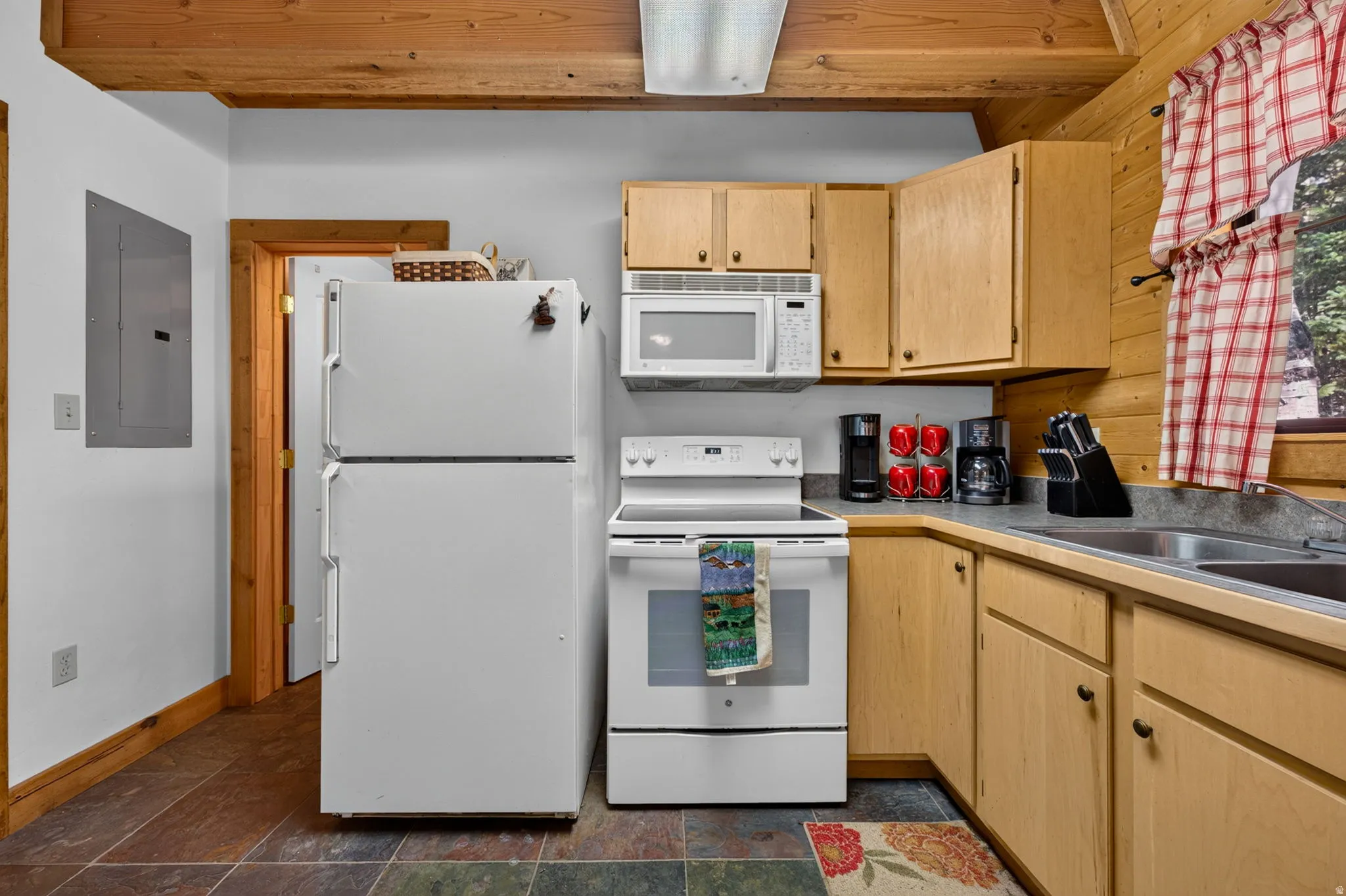 Kitchen featuring light wood cabinetry, white appliances, and a double basin stainless steel sink