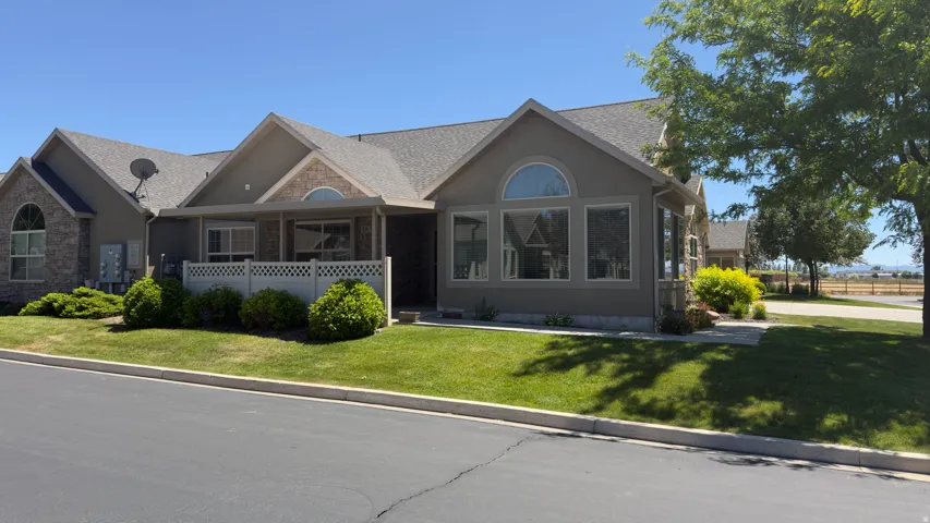 Stucco and stone exterior featuring a covered porch, multiple arched windows, and a manicured lawn