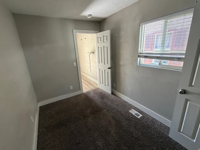 Carpeted room with a window featuring horizontal blinds