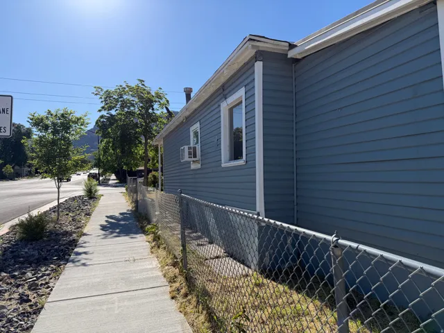 Exterior featuring blue horizontal siding, white trim, and a chain-link fence